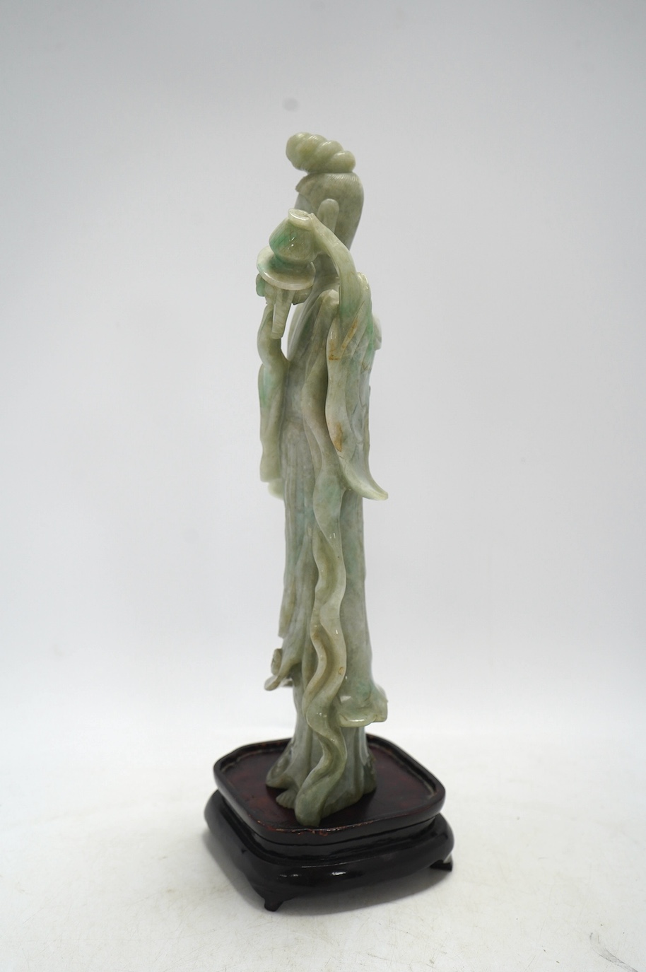 A Chinese jadeite carving of Guanyin, on associated hardwood stand, 38cm high. Condition - fair